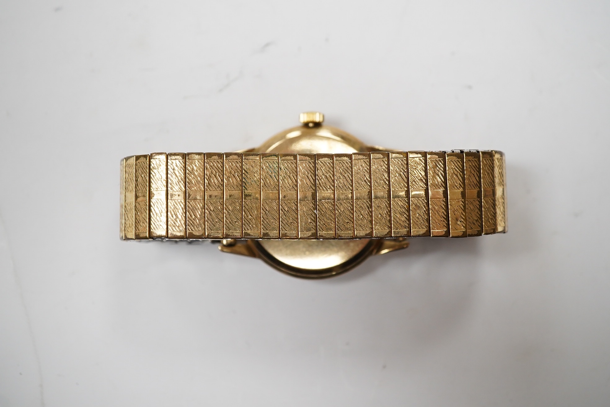 A gentleman's yellow metal Omega manual wind wrist watch, with baton numerals, case diameter 34mm, on an associated rolled gold flexible strap. Condition - fair